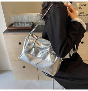 Sac cabas argenté métallisé avec nœuds et bandoulière chaîne porté par le mannequin
