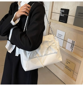 Détail du sac cabas en cuir gaufré blanc avec nœud décoratif et bandoulière chaîne argentée