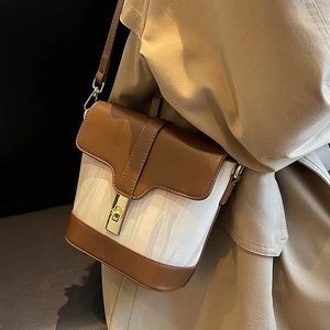 Brown leather and white herringbone bucket bag with gold lock on a khaki trench coat