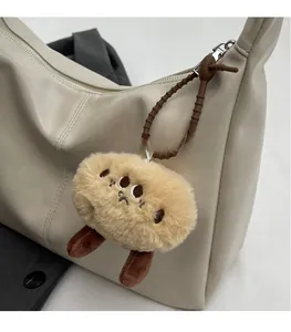 Nahaufnahme eines flauschigen Plüsch-Anhängers mit dunkelbraunem Silikonband an einer Tasche
