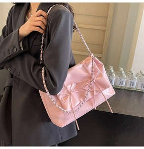 Détails d'un sac cabas rose avec nœuds décoratifs et bandoulière en chaîne argentée