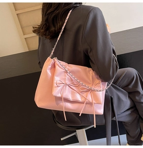 Sac fourre-tout rose avec texture plissée et nœuds décoratifs porté à l'épaule du mannequin