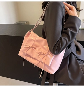 Détail du sac cabas en cuir plissé rose avec des nœuds et une bandoulière chaîne