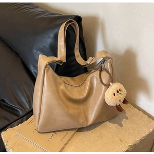 Detailansicht der kamelfarbenen Ledertasche mit weicher Textur und Bärenanhänger