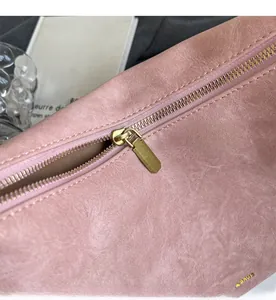 Close-up of smooth gold zipper and rose pink textured leather on tote bag detail