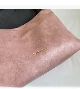 Detail of pink faux leather tote bag with crinkled texture and gold fashion logo