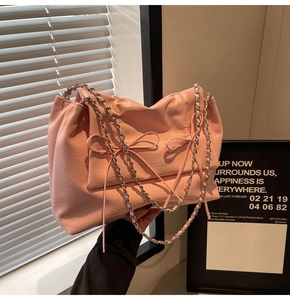 Gros plan détaillé du sac cabas rose avec nœuds décoratifs et bandoulière en chaîne argent