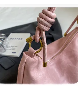 Detail of pink tote bag showing unique knotted handle and circular gold hardware