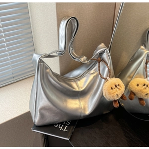 Detail der silbernen Metallic-Hobo-Tasche mit süßem Kartoffel-Plüsch-Anhänger im Wohnambiente