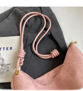 Detail of pink faux suede tote showing knotted cord handle and gold metallic zipper