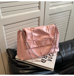 Détail du sac à bandoulière en cuir plissé rose avec nœuds décoratifs et chaîne en métal