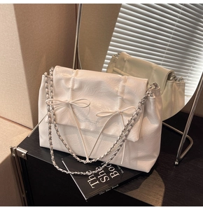 Détail du sac cabas blanc en cuir plissé avec des nœuds décoratifs élégants