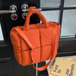 Orange quilted puffer tote bag with padded handles and adjustable strap for women