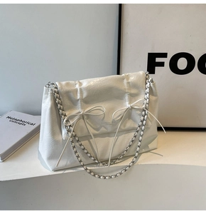 Détail du sac cabas en cuir verni blanc plissé avec nœuds et bandoulière chaîne argent