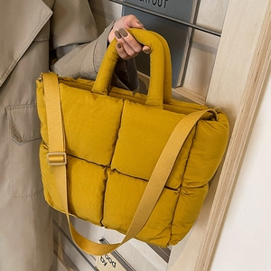Yellow quilted puffer tote bag with adjustable strap shown in a modern casual lifestyle setting