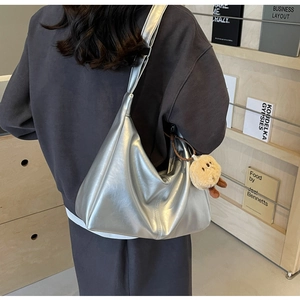 Silberne Hobo-Tasche mit mattem Metallic-Glanz und einem süßen Plüschbären-Anhänger