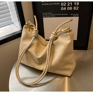 Detail of cream tote bag featuring soft leather texture and golden metal knot hardware