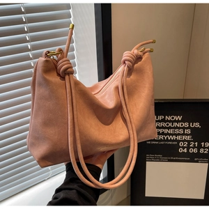 Detail of pink tote bag showing the textured faux leather and knotted rope strap with gold tips