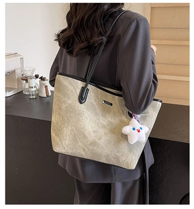 Détail du grand sac cabas gris avec fines lanières noires et breloque en forme d'étoile
