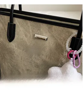 Gros plan d'un sac cabas en toile vintage avec bordures en cuir noir et pendentif