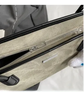 Détail de la fermeture éclair en métal argenté et du logo sur un sac cabas gris