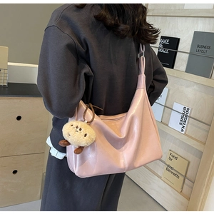 Rosa Hobo-Schultertasche aus Kunstleder mit süßem Plüsch-Anhänger getragen von einem Modell