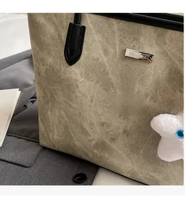 Détail d'un grand cabas vert olive avec texture plissée, logo argenté et charme étoile