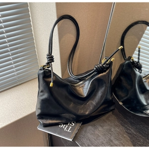 Detail of black soft leather hobo bag with unique knot design and metallic accents