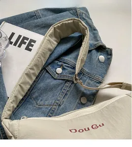 Detail of cream nylon crossbody bag featuring padded shoulder strap and red logo