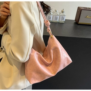 Close-up of pink soft leather tote bag showing pleated texture and knotted shoulder strap