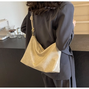 Detail of a large khaki hobo tote bag in soft leather with zipper and decorative knot