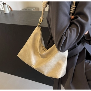 Detail of the cream hobo bag showing the knotted shoulder strap and textured leather finish