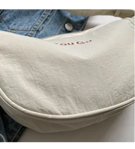 Detail of soft cream nylon fabric with red letter print on a casual crossbody bag