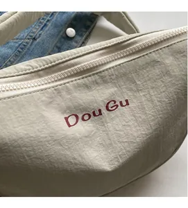 Detail of beige nylon half-moon crossbody bag with resin zipper and burgundy logo