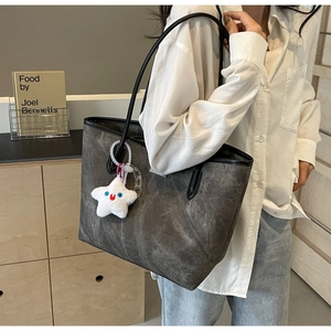 Détail d'un grand sac cabas avec texture gris foncé et breloque étoile sur l'épaule