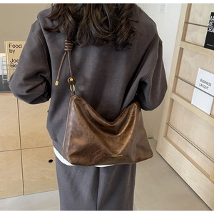Brown vintage faux leather hobo tote bag with knotted shoulder strap shown on model