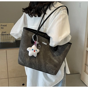 Détail du grand sac cabas gris foncé avec breloque étoile et plaque de marque en métal