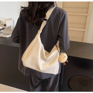 Detail der minimalistischen cremefarbenen Tragetasche im Hobo-Stil mit Bärenanhänger