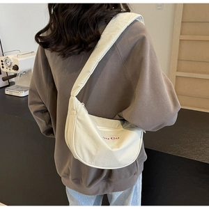 Detailed back view of a cream nylon crescent crossbody bag with red letter embroidery