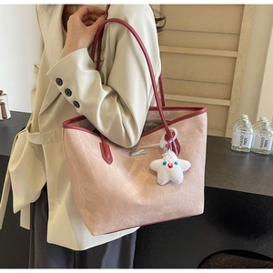 Détail d'un cabas en daim rose avec bordure en cuir rouge et charm étoile en peluche