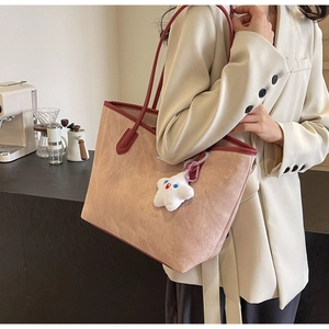 Détail d'un grand sac cabas en daim avec bandoulières contrastées et breloque étoile