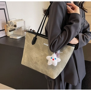 Détail du sac cabas gris-vert avec texture plissée et logo argenté sur la bandoulière