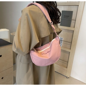 Model wearing a pink nylon crescent bag with wide shoulder strap and Dou Gu logo