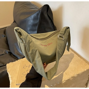 Detail of army green nylon crescent bag with Dou Gu logo and adjustable wide strap