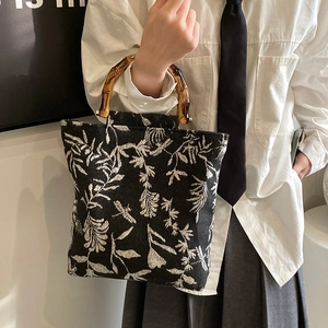 Sac cabas floral en toile avec anses en bambou vintage porté par un mannequin en studio