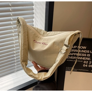 Detailed macro view of beige nylon crossbody bag with Dou Gu branding and metal buckle