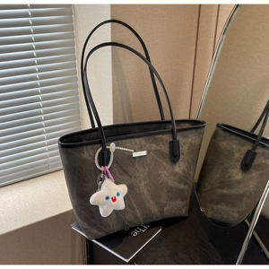 Détail du cabas gris foncé avec logo métallique et breloque peluche étoile blanche