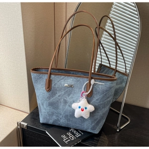 Détail d'un sac cabas bleu texturé avec anses en cuir marron et charme étoile