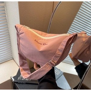 Detailed view of pink nylon crescent bag with wide strap and silver metal hardware