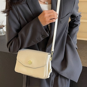 Elegant cream leather crossbody flap bag with gold metal hardware and slim strap on model